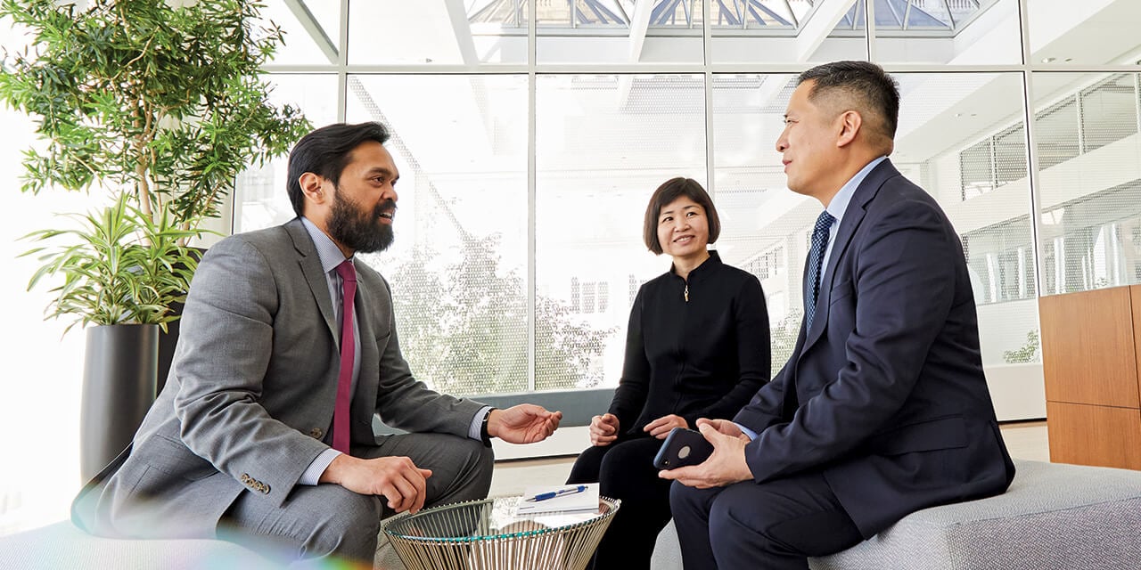 Three associates from the Chautauqua team engaged in conversation in an open office area